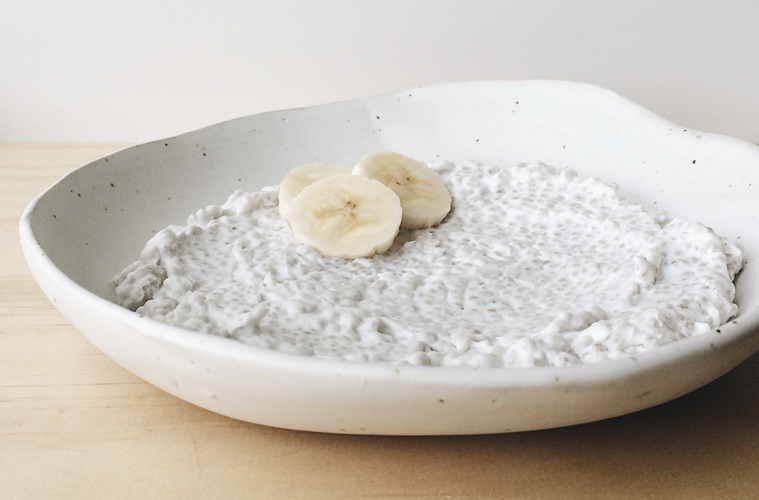 Coconut Chia Pudding in a white shallow bowl with three slices banana.