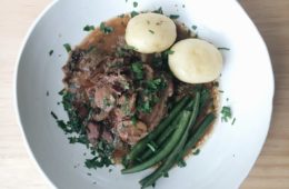 coq au vin with potatoes and green beans on a plate