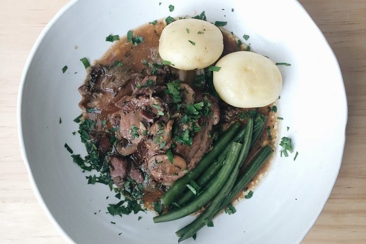coq au vin with potatoes and green beans on a plate