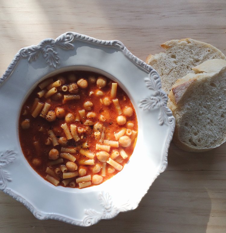Pasta con ceci in a white bowl and two slices of bread