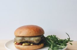 Cheeseburger with rocket on a white plate
