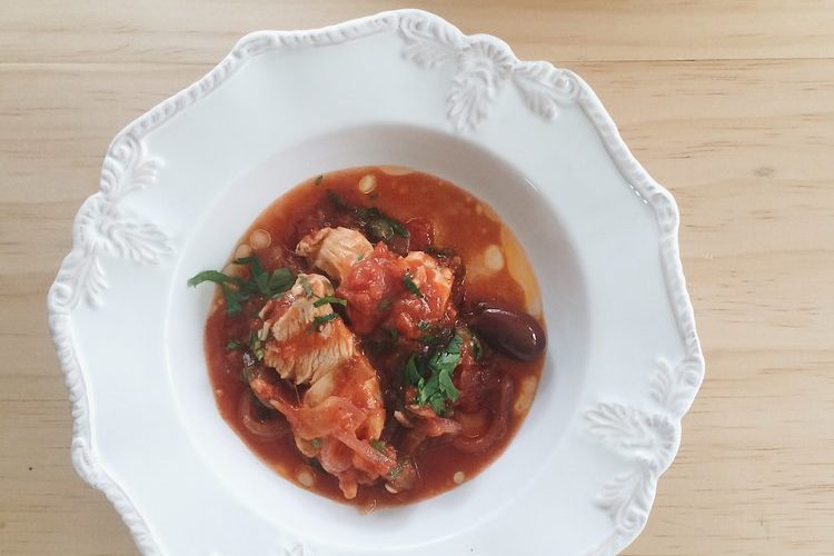 tomato simmered chicken with olives in a white bowl