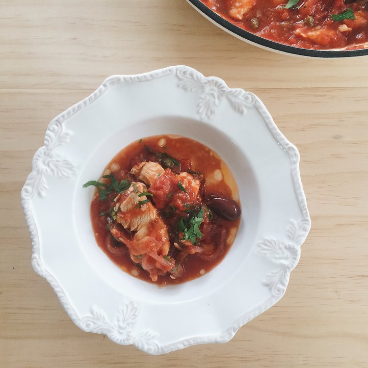 tomato simmered chicken with olives in a white bowl