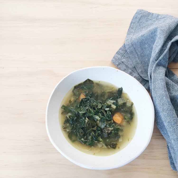Green Soup with Ginger and Miso in a white bowl with a grey napkin next to it