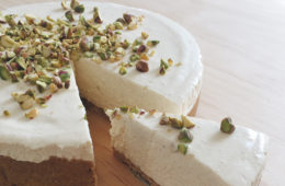 Honey and Cardamom Cheesecake with a piece cut out, on a wooden surface