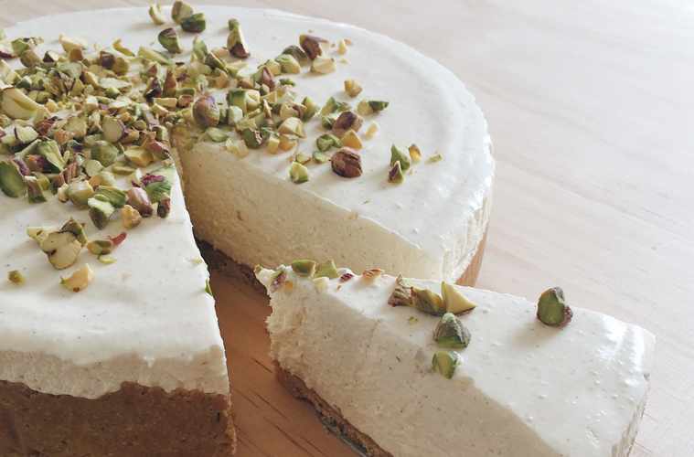 Honey and Cardamom Cheesecake with a piece cut out, on a wooden surface