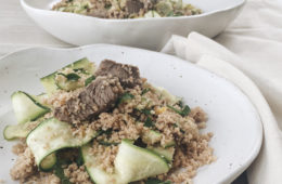 Moroccan Lamb with Lemon Couscous on a white plate with a larger bowl of lamb couscous in the background and a white napkin around