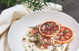 Semolina with Rhubarb Compote in a white bowl sprinkled with pumpkin seeds and macadamia nuts