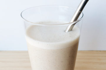 banana and tahini smoothie in a glass with a metal reusable straw