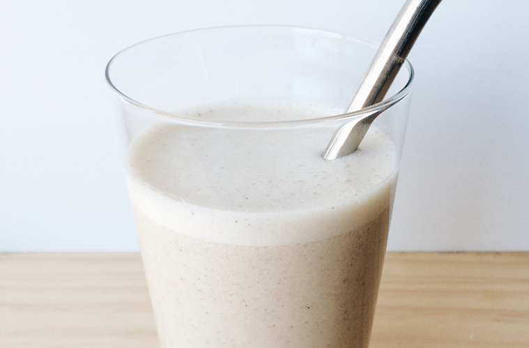banana and tahini smoothie in a glass with a metal reusable straw
