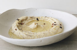 Hummus in a white bowl sprinkled with chilli and chia seeds