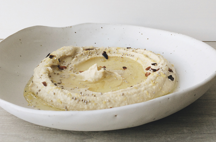 Hummus in a white bowl sprinkled with chilli and chia seeds