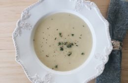 Potato and leek soup in a white bowl with a grey serviette