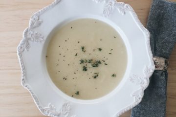 Potato and leek soup in a white bowl with a grey serviette