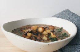 Brown Mushroom Soup in a white bowl with grey napkin on the side