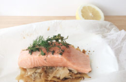 Salmon and Fennel Parcels wrapped in baking paper on a white plate with a piece of lemon in the background