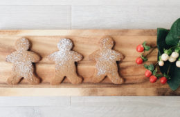 Buckwheat Gingerbread Men on a wooden board with some red and white flowers on the side