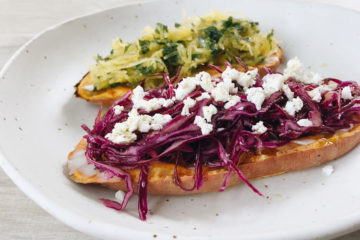 Two slices Sweet Potato Toast with red cabbage and feta and spaghetti squash topping on a white plate