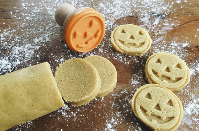 halloween cookies being stamped with a cookie stamp that makes scary pumpkin faces