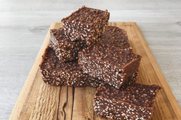 Choc Tahini Amaranth Crunch squares piled on a wooden board