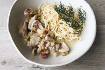 coq au Riesling with spaghetti and dill on a white plate