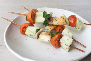 greek salad skewers on a white plate on a wooden surface