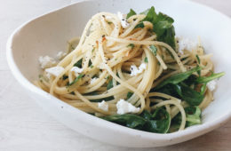 spaghetti with rocket and soft goats cheese in a white bowl