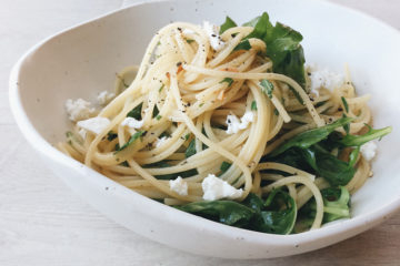spaghetti with rocket and soft goats cheese in a white bowl