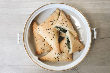 spinach and feta triangles in a vintage bowl on a wooden surface