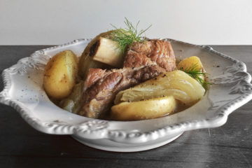 Lamb Shanks with potato and Fennel in a white bowl on a black wooden surface