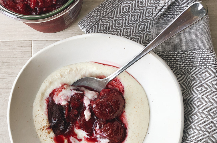 Plum Compote on semolina in a white bowl with a spoon tucked in