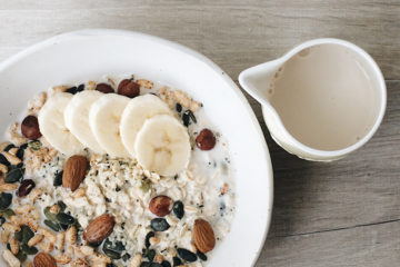 Power Breakfast Muesli in a white bowl with banana and nut milk in a jug next to the bowl