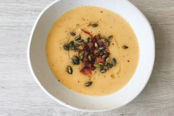 Two Potato Soup in a white bowl with bacon bits and pumpkin seeds