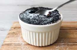 self saucing chocolate pudding in a ramekin with a spoon tucked in on a wooden board