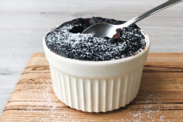 self saucing chocolate pudding in a ramekin with a spoon tucked in on a wooden board