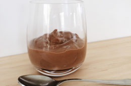 Bouillie au Chocolat in a glass on a wooden surface with a spoon in front