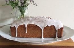 Omi's Lemon Cake on a white plate with flowers in the background