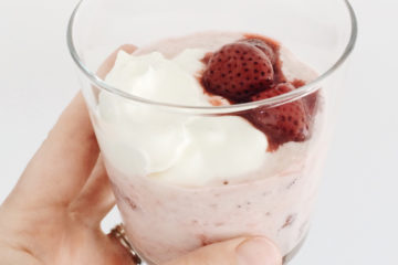 Overnight Strawberry Oats in a glass held by a hand