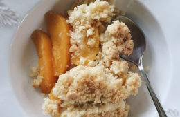 Peach and Coconut Crumble on a white plate with a spoon