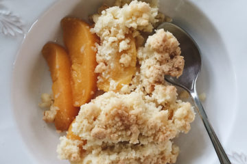 Peach and Coconut Crumble on a white plate with a spoon