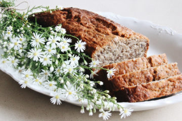 healthy banana bread on a white plate with white field flowers