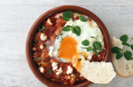 easy baked eggs in a terracotta bowl with oregano and slices of bread