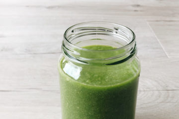 spinach and rockmelon smoothie in an open jar on a wooden surface