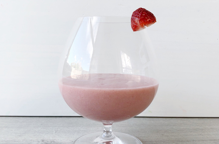 strawberry and coconut smoothie in a glass on a wooden surface