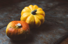 two pumpkins on a grey surface
