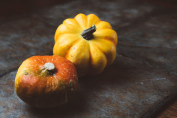 two pumpkins on a grey surface