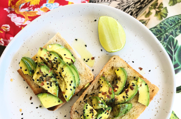 avocado toast on a white plate with lime
