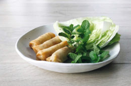 Springrolls on a white plate with lettuce and mint