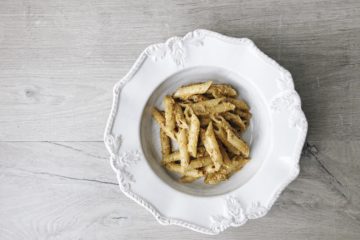 almond tomato and garlic pesto with penne on a white plate