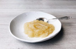 stewed apple on a white plate with a small silver spoon